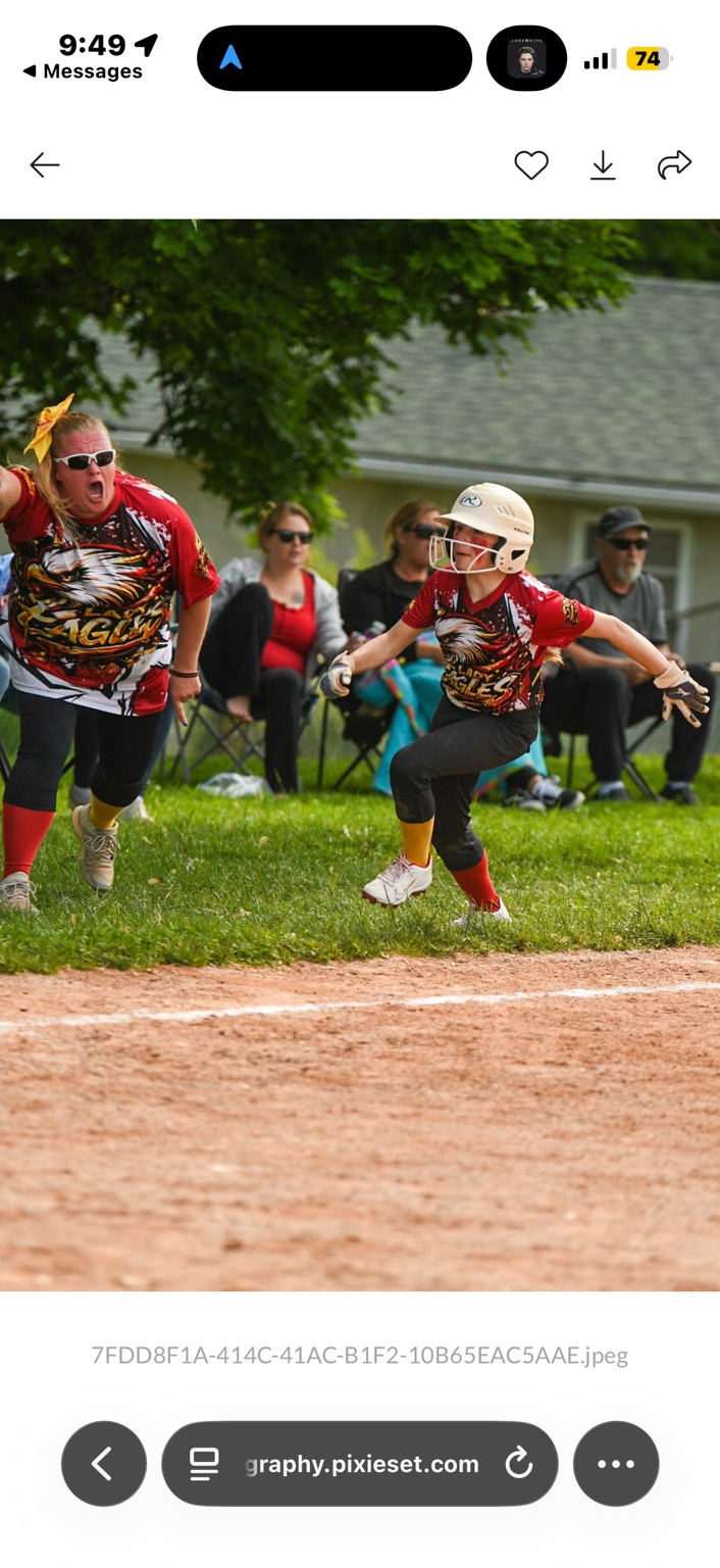 Lady Eagles runner taking off from a base with her coach cheering